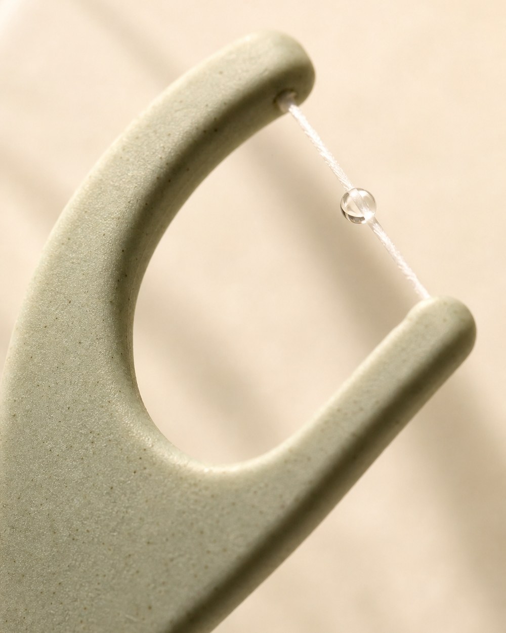 Macro close-up of the tēra floss pick head showing taut shred-resistant floss